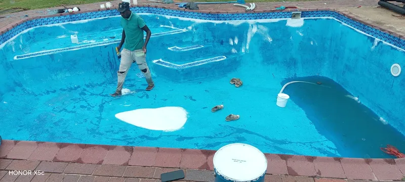 Pool painting in progress with worker applying new coat